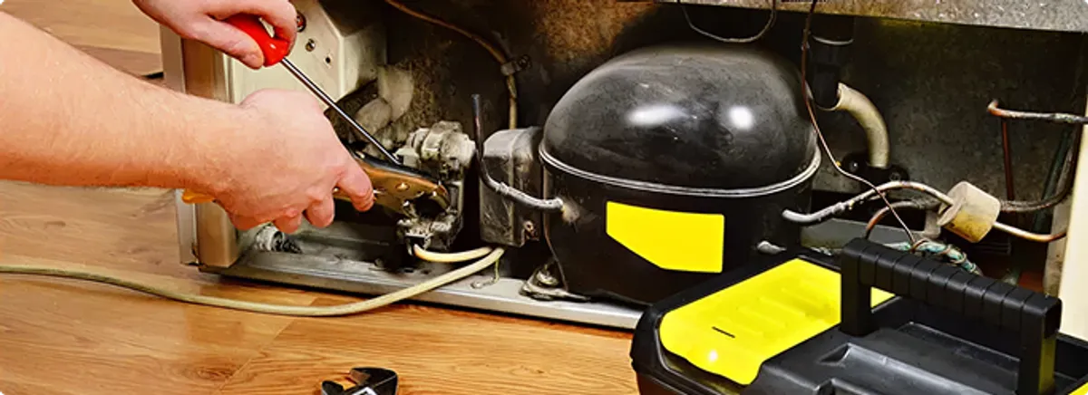 Refrigerator repair technician fixing the compressor and wiring in Bedford, TX