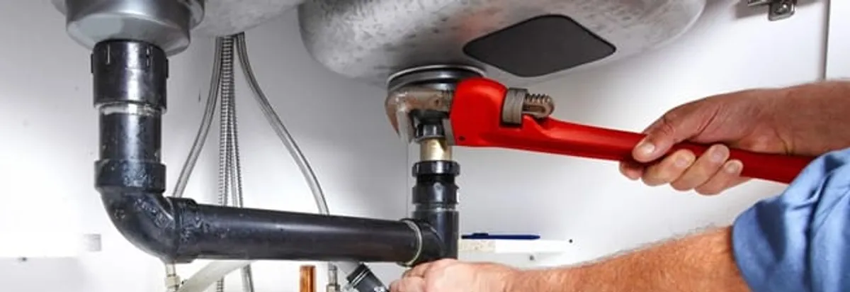 Garbage disposal repair technician tightening the sink drain and disposal connection in Fort Worth, TX
