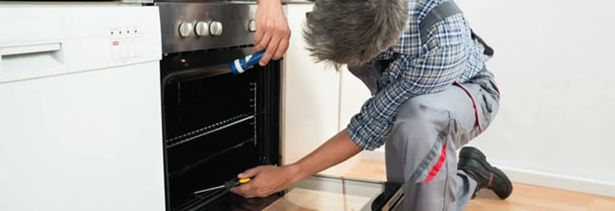 Oven repair technician inspecting and servicing an electric oven in Fort Worth, TX
