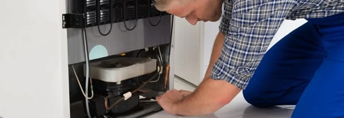 Refrigerator repair technician servicing the compressor and condenser area in Fort Worth, TX